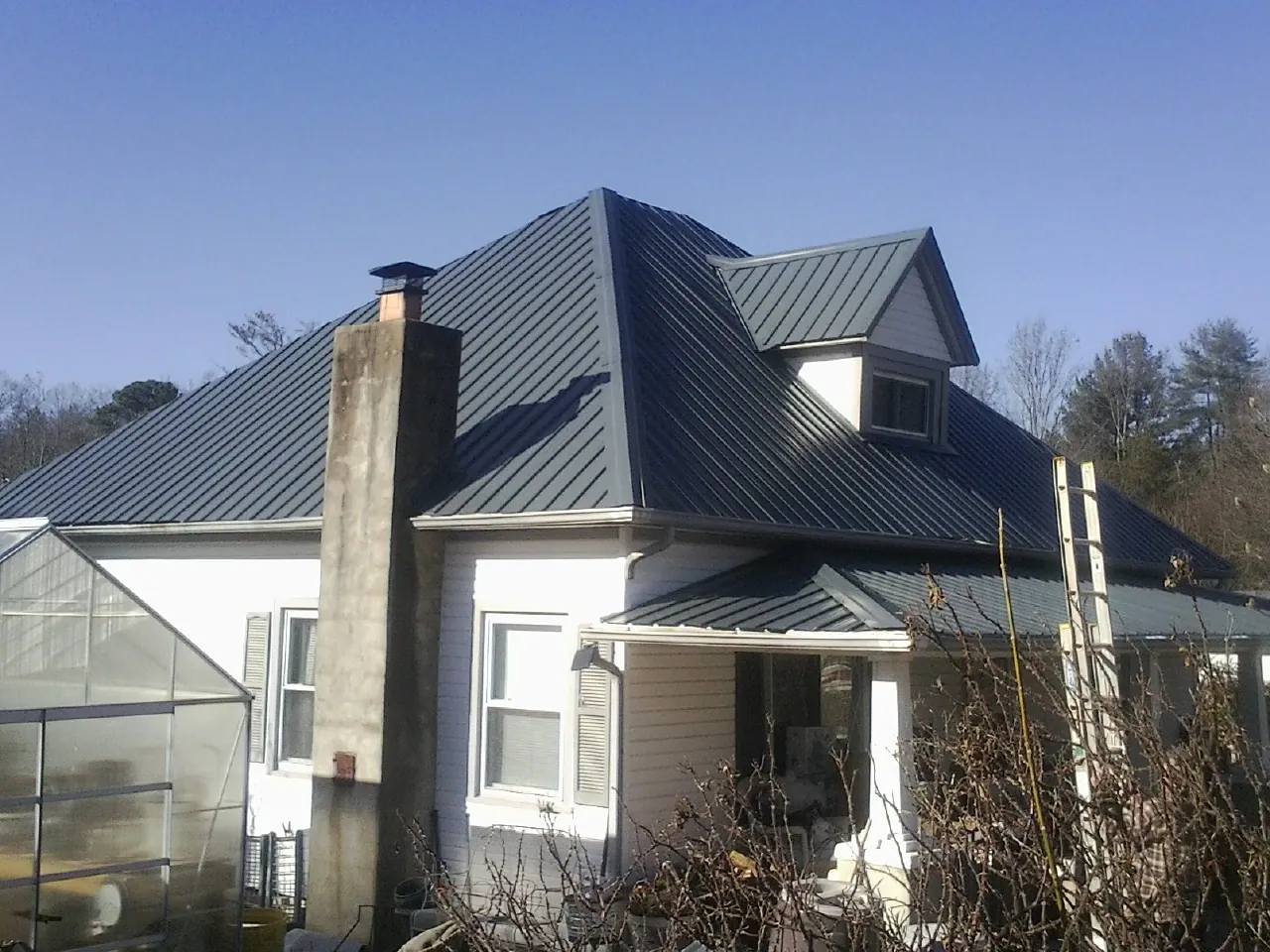 Dark blue standing seam metal roof on a white farmhouse with dormer — Slate & Tile Roof Repair by Roofing Brothers in Laguna Hills