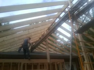 Rafters going up over a new addition with a worker on the wall in Laguna Hills