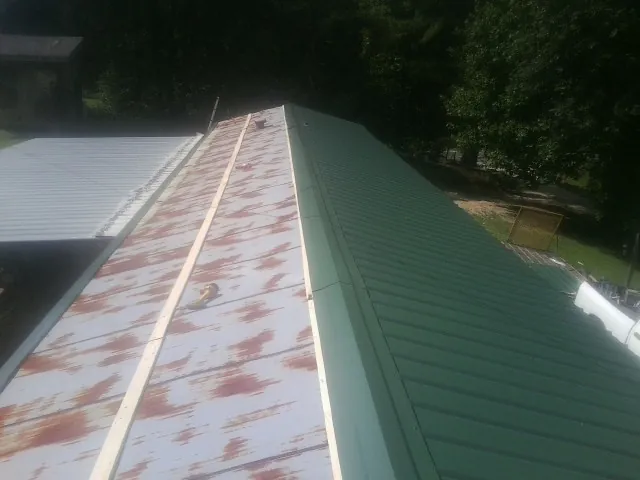 Old rusted panels beside newly installed green metal roofing — Wind Damage Roof Repair by Roofing Brothers in Laguna Hills