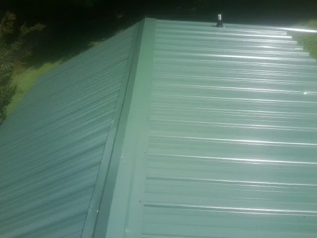 New green metal panels meeting at the ridge of a roof — Flat Roof Repair work by our crew in Laguna Hills