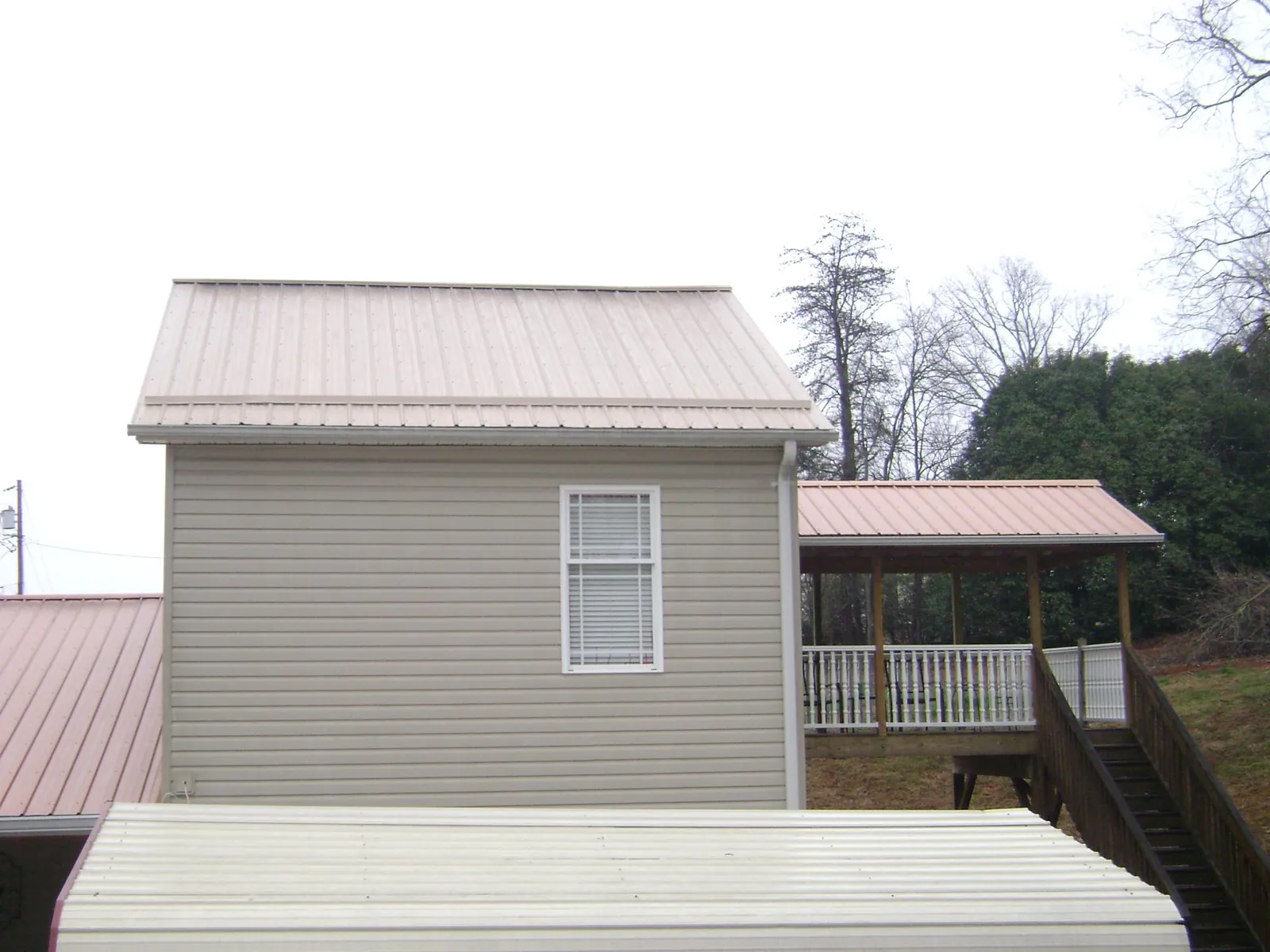 Tan metal roofs on a two story addition and attached porch, from a Roof Replacement job in Laguna Hills