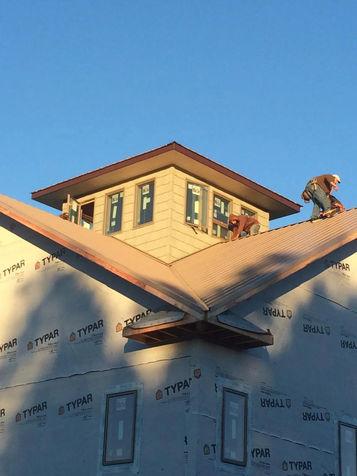 Roofers working around a rooftop cupola on a new metal roof at sunset — Roof Waterproofing in Laguna Hills by Roofing Brothers